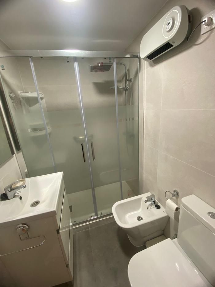 Baño después de la reforma en Sevilla con mampara de ducha y aire acondicionado